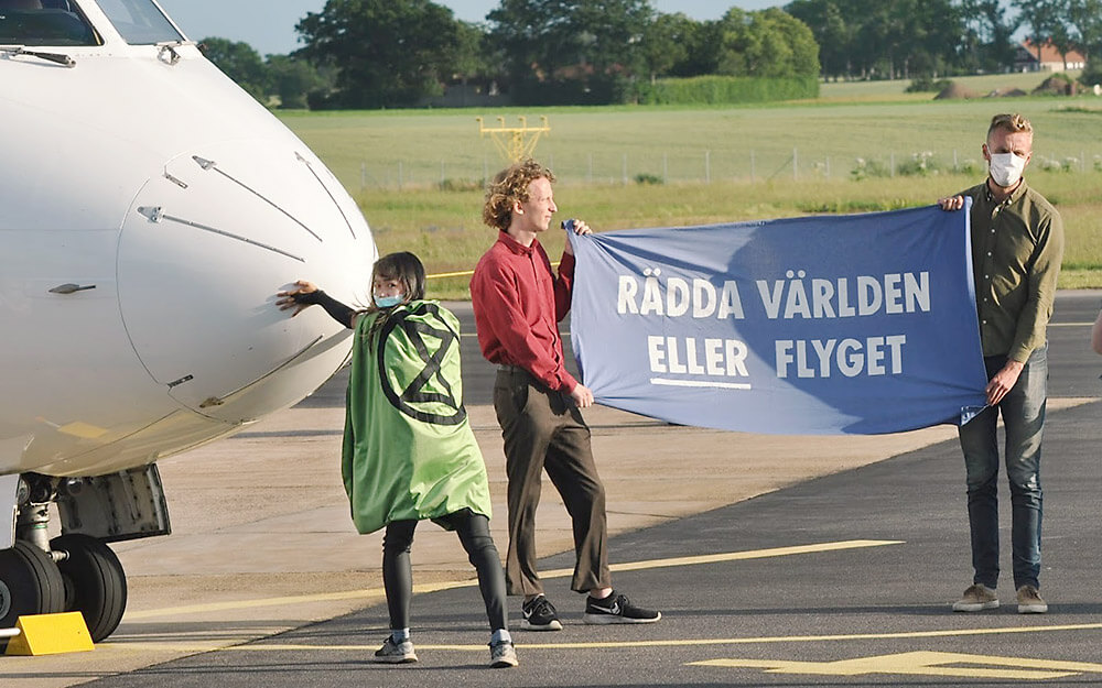 Photograph of action with rebels holding banner "Save the world ORaviation."