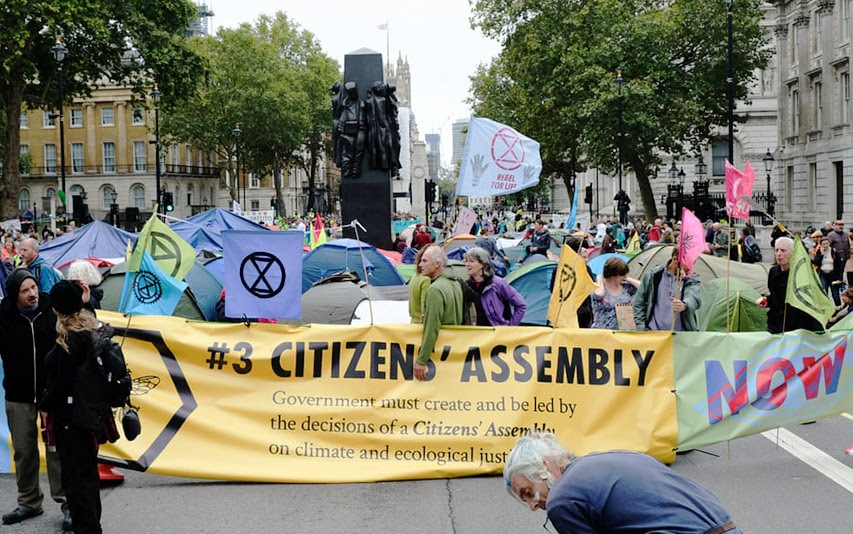 manifestantes seguram num cartaz da XR que diz "#3 rua da AssembleiaCidadã"